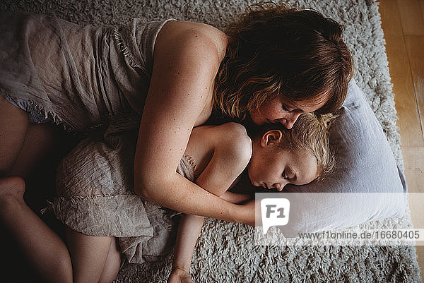 Mutter und Tochter umarmen schlafend auf dem Boden im Schlafzimmer