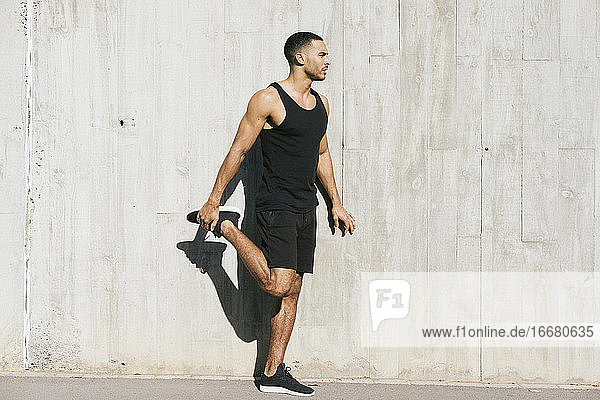 Full length of African American male athlete stretching legs