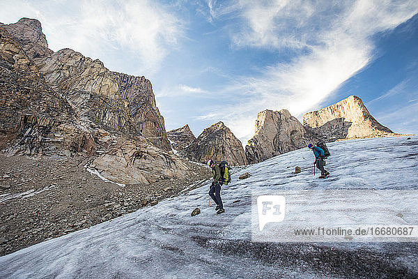 Two mountain climbers traverse a glacier below Mount Asgard.