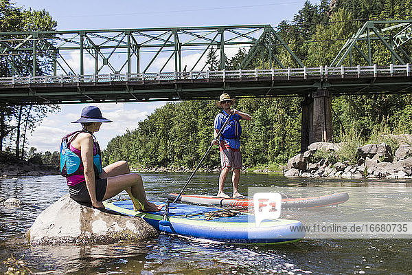 A young couple enjoy the river on their SUPs in Oregon.