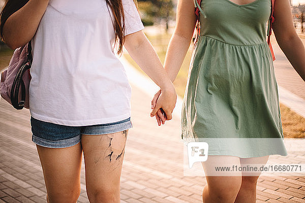 Mittelteil eines lesbischen Paares  das sich beim Spaziergang in der Stadt an den Händen hält