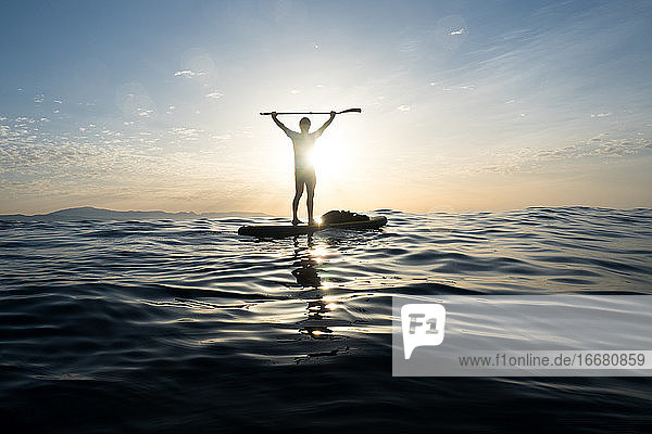 Konzept: Sieg und Glück. Mann auf einem Paddle-Surfbrett. In t