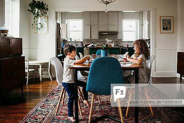 Young kids sitting at dining table doing arts and crafts together
