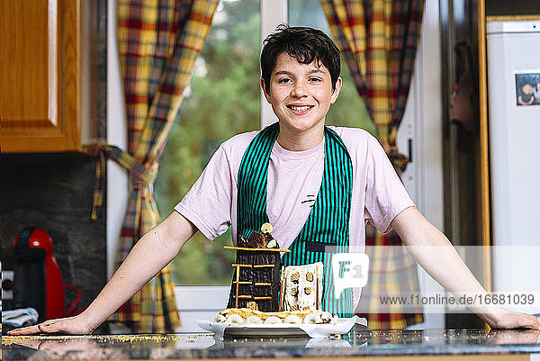 Junger Mann lächelnd und mit Blick auf die Kamera in der Küche mit Schokoladenkuchen