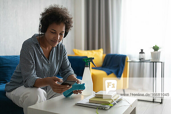 Schwarze Hausfrau mit Kopfhörern und Smartphone
