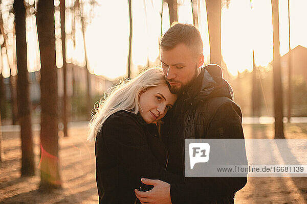 Junges glückliches Paar in der Liebe romantisch stehend im Park bei Sonnenuntergang