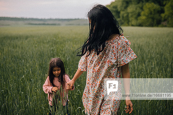 happy Mother walking with child in field at dusk
