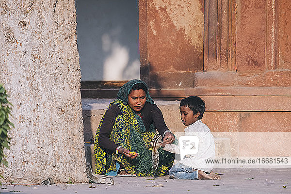 Indische Frau und ihr Sohn füttern ein Eichhörnchenpaar am Agra-Fort.