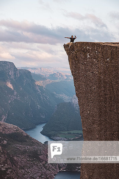 Mann sitzt am Rand einer Klippe am Preikestolen  Norwegen