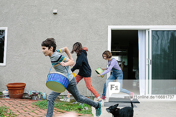 Geschwister rennen mit ihren leeren Osterkörbchen nach draußen  um Eier zu sammeln