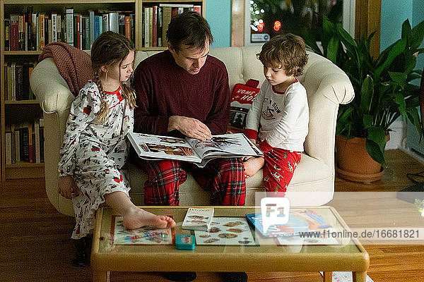 Vater liest seinen Kindern zu Weihnachten eine Gutenachtgeschichte vor