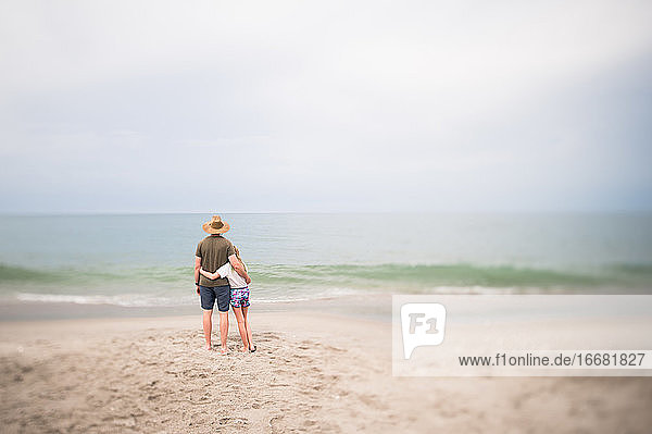 Mann und junges Mädchen stehen mit Blick auf den Ozean in Indialantic FL