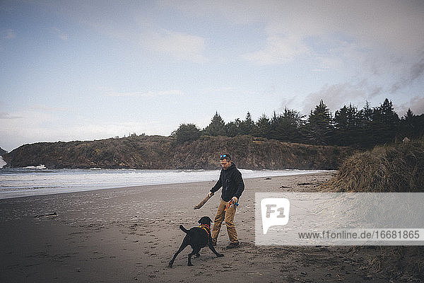 Ein Mann spielt mit einem Hund am kalifornischen Strand