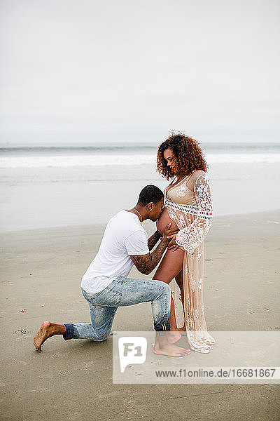 Mixed Race Couple on Beach  Kissing Baby Belly