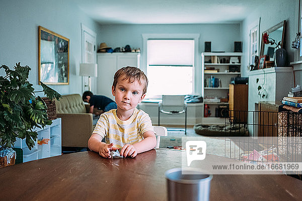 Porträt eines kleinen Jungen  der am Küchentisch sitzt und auf das Essen wartet