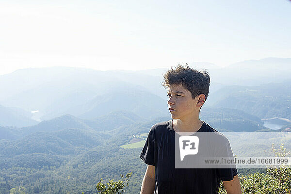Portrait of a young male with black t-shirt standing against mountains