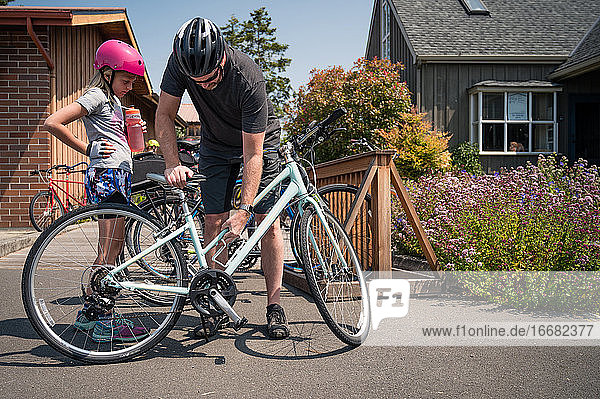 Vater und Tochter tragen Fahrradhelme und bereiten sich auf eine Fahrradtour vor