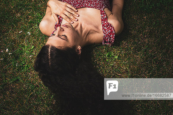 junge Frau mit langem glattem Haar im Gras liegend