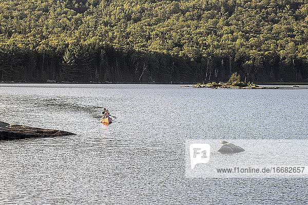 Zwei Personen paddeln mit dem Kanu über den felsigen Bald Mountain Pond in Maine