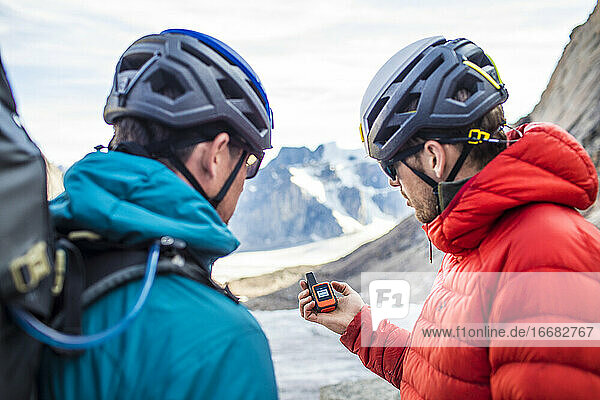 Zwei Bergsteiger benutzen ein GPS  um sich im Gebirge zurechtzufinden.