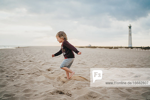 Kind Junge Kind spielt am Strand an einem bewölkten Tag