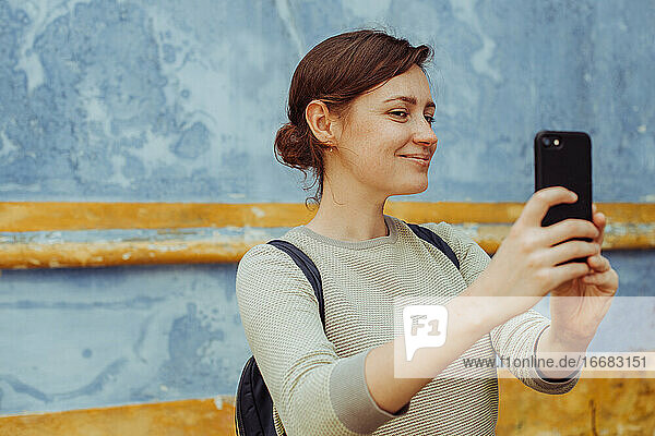 Young woman blogger taking selfies or photos with modern smartphone
