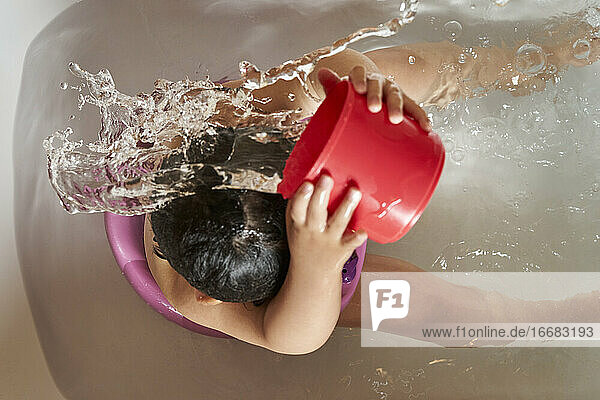 Das Kind wäscht sich unter der Dusche den Kopf.