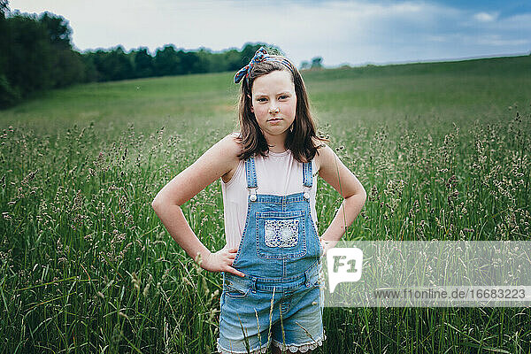 Teen Girl in Overall Shorts Standing in Grassy Field in the Midwest