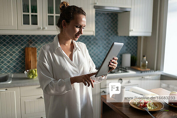 Geschäftsfrau  die beim Frühstück auf einem Tablet surft
