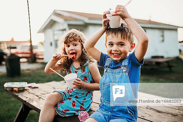 Close up of two young kids eating snow cones in summer