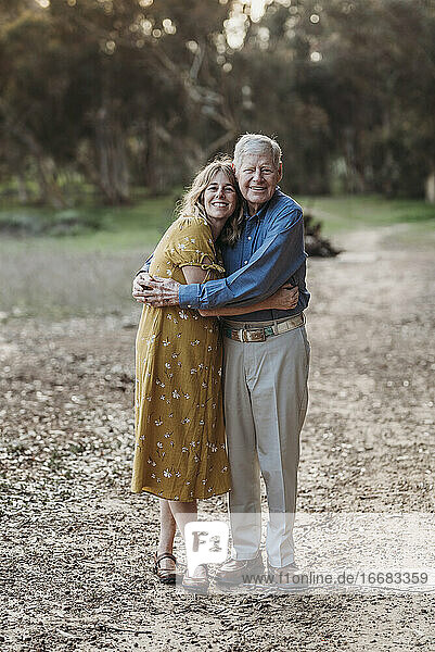 Porträt einer erwachsenen Frau und eines älteren Vaters  die sich im Park umarmen