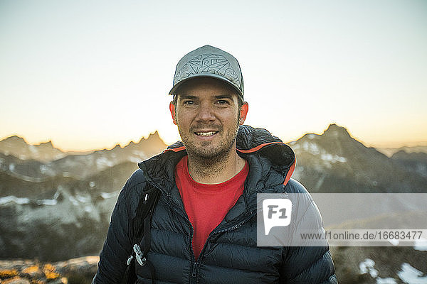 Portrait of back lit man standing at sunset in mountains.