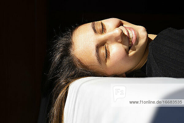 Frau beim Sonnenbad auf einem weißen Bett.