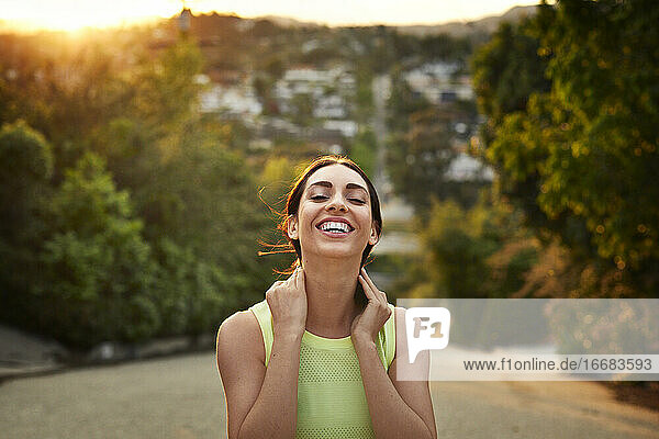 Smiling tired woman standing on road during sports training