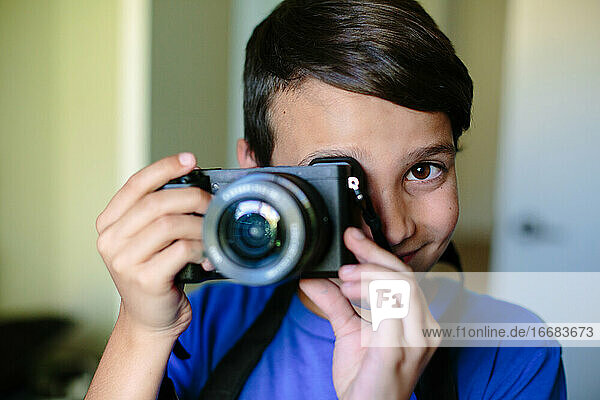 Portrait of a boy holding a camera up to his eye