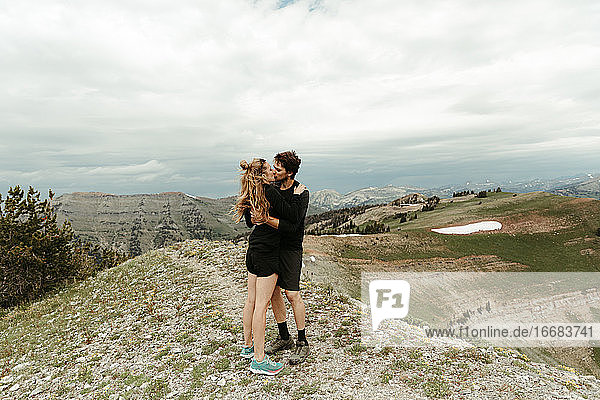 newly engaged white couple kiss on a mountain top in wyoming