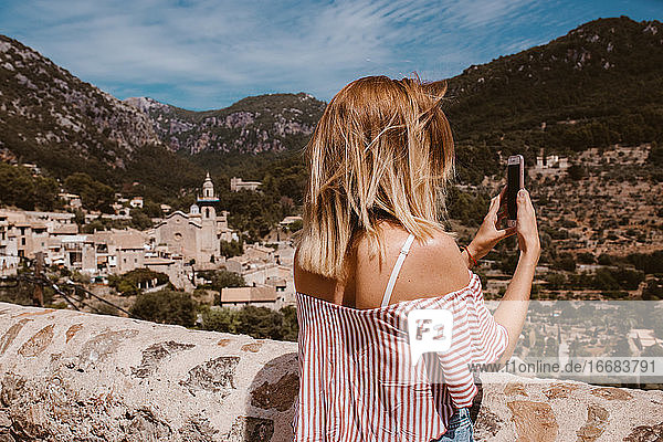 Frau auf einer Reise  die ein Foto mit dem Handy von der Landschaft auf Mallorca macht