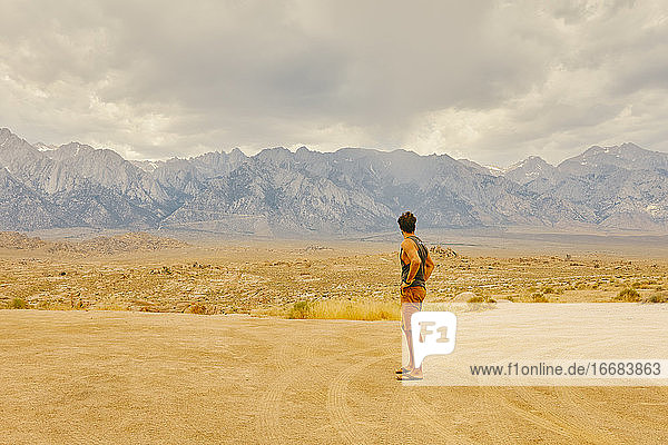 Junger Mann in der kalifornischen Wüste mit Blick auf die Berge von Alabama Hills.