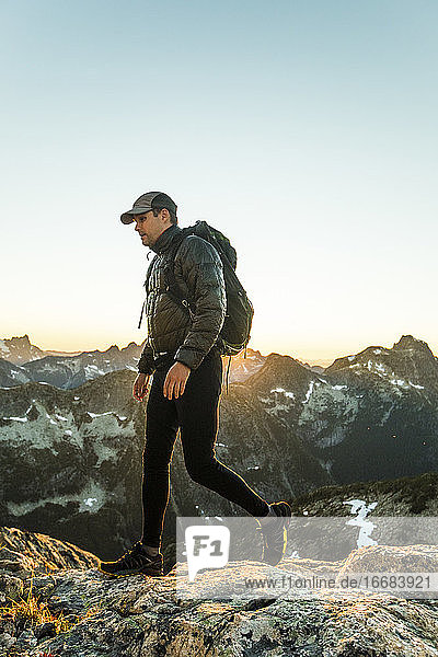 Aktiver Mann in Bewegung beim Überqueren eines hohen Bergpasses mit Rucksack