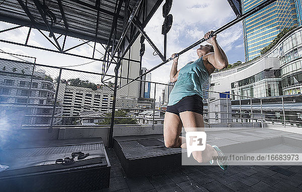 Frau trainiert auf dem Dach eines Fitnessstudios in Bangkok