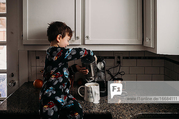 Junge sitzt auf dem Tresen und kocht Kaffee für seinen Vater