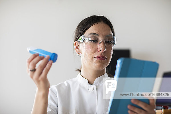 Wissenschaftlerin mit Laborbrille  Tablette und Röhrchen in einem Labor