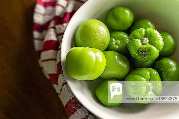 a bowl of fresh tomatillos sitting on a kitchen table