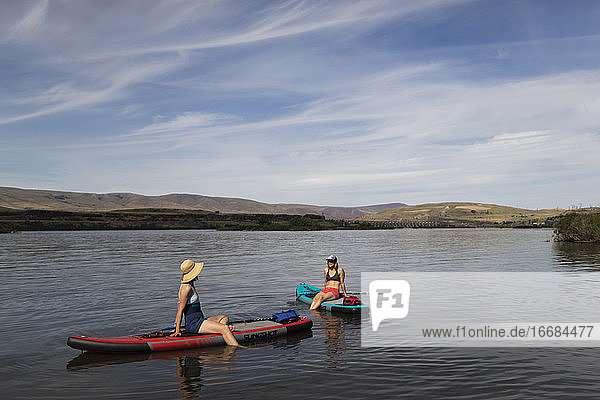 Two female friends sit on their SUPs on the Columbia River in Oregon.