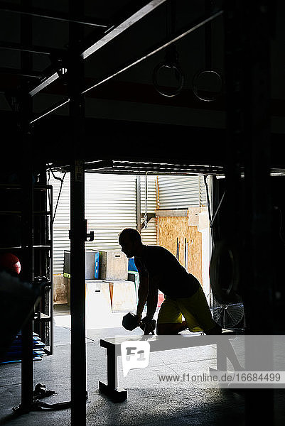 Junger Mann trainiert in einem Garagen-Fitnessstudio mit Hantel