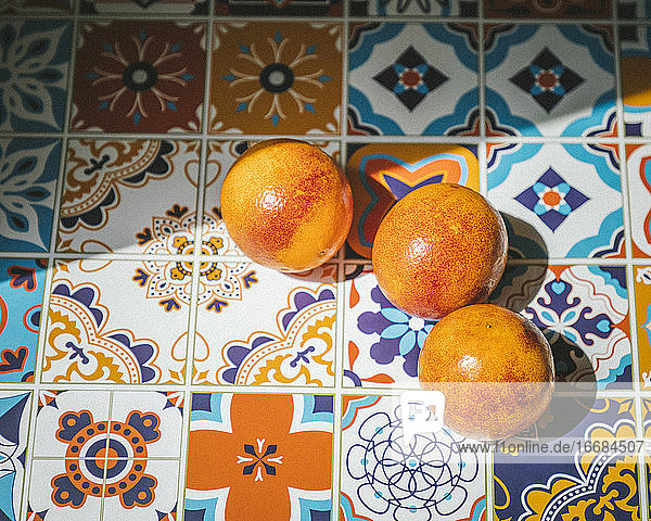 Orangen auf einem bunten Keramiktisch  unter der Sonne