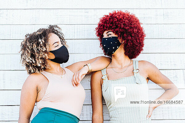 Two latin women with mask in a carefree attitude on a white background