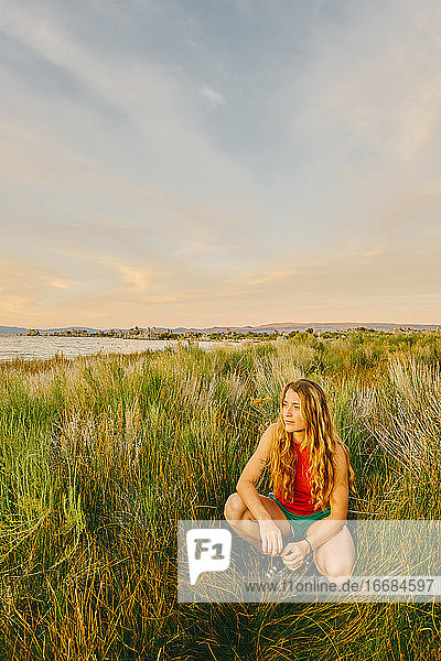 Junge Frau sitzt im hohen Gras am Mono Lake in Nordkalifornien.