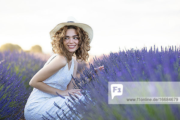 woman with curly hair wearing a hat in a lavender field