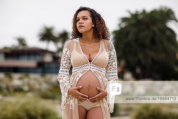 Junge schwangere Frau posiert am Strand